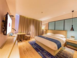 una camera d'albergo con un letto grande e una scrivania di Echarm Hotel Putian Chengxiang Wenxing Pedestrian Street Branch a Putian