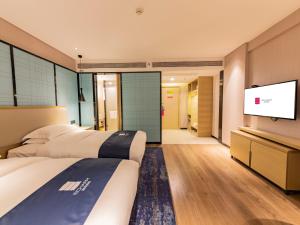 una camera d'albergo con due letti e una TV a schermo piatto di Echarm Hotel Putian Chengxiang Wenxing Pedestrian Street Branch a Putian Altre 5 foto