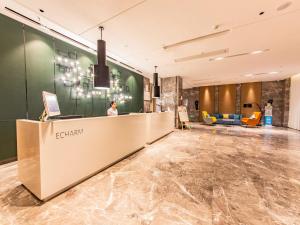 Una donna in piedi alla reception in una hall di Echarm Hotel Putian Chengxiang Wenxing Pedestrian Street Branch a Putian