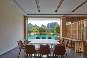 a dining room with a table and chairs and a pool at Yangshuo Lakeside Inn in Yangshuo