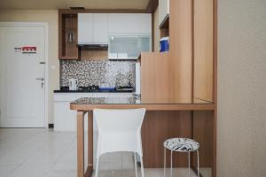 a kitchen with a table and two white chairs at Comfortable and Homey 1BR Apartment at Silkwood Residences By Travelio in Tangerang