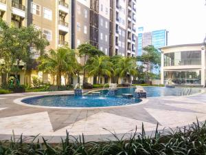 a large pool in the middle of a courtyard with buildings at Comfortable and Homey 1BR Apartment at Silkwood Residences By Travelio in Tangerang