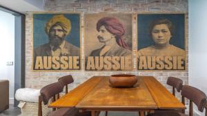 a table with three posters on a brick wall at Aunty Olive's - Pearl Beach in Pearl Beach +14 photos