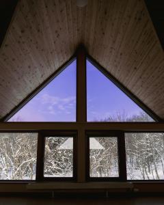 a window in a room with snow covered trees at Cottage with views of the Niseko mountain range - Mountain View Niseko in Niseko