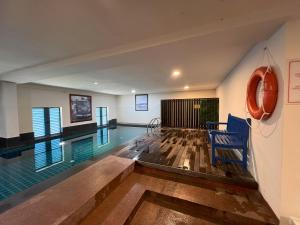 a swimming pool with a blue chair in a room at JOM at deRiviera Self check-in in Malacca
