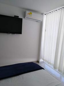 a room with a bed and a tv and a window at Casa hermosa y privada en Santa Marta in Gaira +2 photos