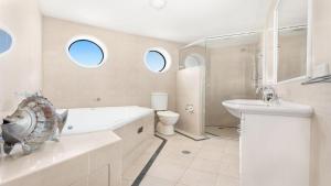 a white bathroom with a sink and a toilet at Le Point 702 Luxury and Views in Forster +17 photos