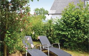 two blue chairs in front of a hedge with roses at Two-Bedroom Holiday Home In Grasten in Gråsten