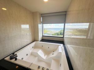 Fair Tale Motel - Sea في مدينة هوالين: حوض استحمام في حمام به نافذة كبيرة
