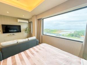 Fair Tale Motel - Sea في مدينة هوالين: غرفة نوم مع نافذة كبيرة مع سرير وتلفزيون