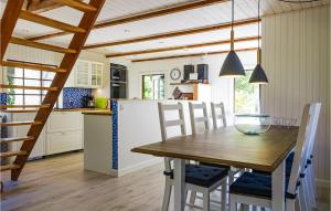 a kitchen with a wooden table with chairs and a refrigerator at Amazing Home In Nexø With Kitchen in Neksø