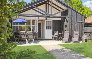 a patio with chairs and an umbrella on a house at Amazing Home In Væggerløse With Kitchen in Marielyst +5 photos
