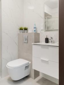 a white bathroom with a toilet and a sink at City Spot Łódź by Aparo - Manufaktura, Nowy Apartament, PlayStation, Miejsce do Pracy, Winda, Balkon in Łódź +13 photos