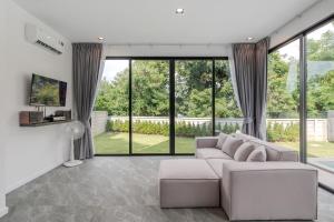 a living room with a couch and large windows at Gina Poolvilla89 Pattaya-Bangsaray to beach 900M in Bang Sare