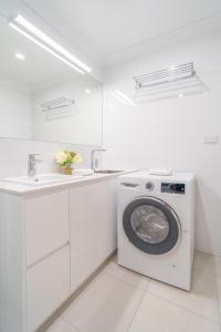 a white laundry room with a washing machine and a sink at Byron Bayside Central Studio Apartments in Byron Bay