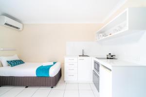 a small white kitchen with a bed in it at Byron Bayside Central Studio Apartments in Byron Bay