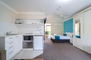 a kitchen with white cabinets and a bed in a room at Byron Bayside Central Studio Apartments in Byron Bay