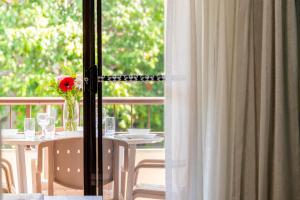 a table with a vase with a red flower on a balcony at Byron Bayside Central Studio Apartments in Byron Bay +100 photos