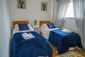 LoughtonにあるLuxury Home Away from Homeのベッドルーム1室(ベッド2台、青いシーツ、タオル付)