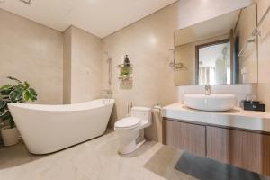 a bathroom with a tub and a toilet and a sink at H-Vista Suites - Hongkong Tower in Hanoi