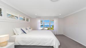 a white bedroom with a bed and a window at 'Coastal Ambience' by HolidayCo in Hardys Bay