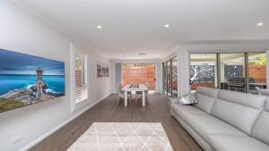 a living room with a white couch and a table at 'Coastal Ambience' by HolidayCo in Hardys Bay