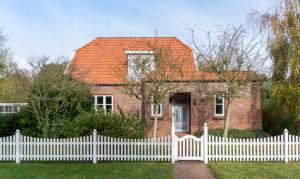 a white picket fence in front of a brick house at Kaapdüne in Spiekeroog