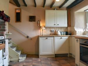 une cuisine avec des placards blancs et un escalier dans l'établissement Thorn Cottage, à Spark Bridge 10 autres photos
