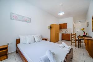 a bedroom with a white bed and a kitchen at Ancient Thera Apartments in Kamari