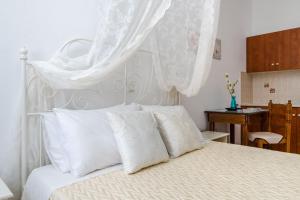 a bedroom with a white bed with white pillows at Ancient Thera Apartments in Kamari +197 photos