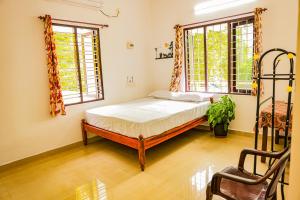 a bedroom with a bed and two windows at Marari Eden Castle in Vayalār