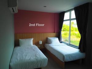 two beds in a room with a window at Sleepwell@naiyang in Nai Yang Beach