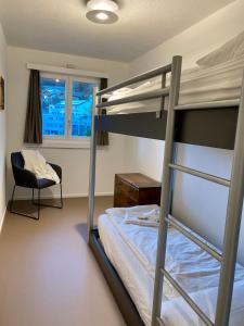 a bedroom with a bunk bed and a chair at house & living junbi in Laax