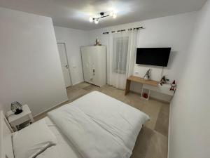 a white room with a bed and a flat screen tv at CLAS Studio in Sibiu