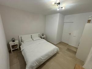 a white bedroom with a white bed and a lamp at CLAS Studio in Sibiu