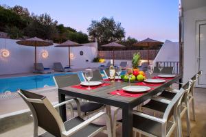 ein schwarzer Tisch mit Stühlen und ein Tisch mit Obst darauf in der Unterkunft Amazing Summer Villa in Kolymbia