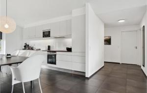 a kitchen with white cabinets and a table and chairs at Holiday Home Ringmosevej Holbæk V in Kisserup