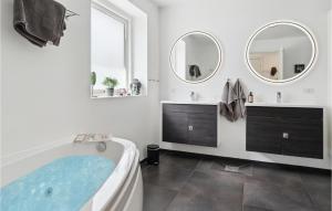 a bathroom with a tub and two mirrors at Holiday Home Ringmosevej Holbæk V in Kisserup +21 photos