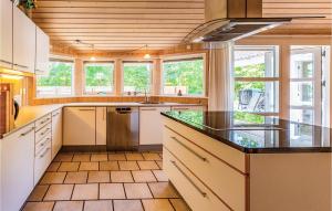 a large kitchen with white cabinets and counters and windows at Holiday Home Hjortestien Højby X in Lumsås