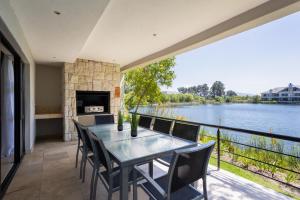 a table and chairs on a balcony with a view of a river at Luxury Lodge 4F Pearl Valley Golf Estate in Simondium