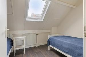 1 dormitorio en el ático con cama y ventana en Duinstraat 10, en Domburg