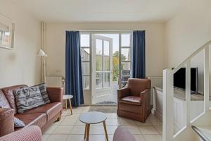 sala de estar con sofá, silla y TV en Duinstraat 10, en Domburg