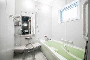 a white bathroom with a green tub and a sink at THE CITYSCAPE in Kita-sanjō