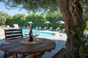 a wooden table with glasses and a bottle of wine at Triantafillas Suites in Afantou