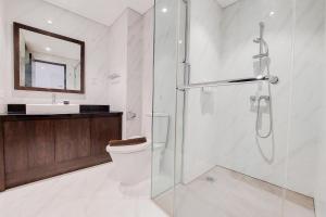 a bathroom with a shower and a toilet and a sink at Homey and Tranquil 1BR Branz BSD City Apartment By Travelio in Tangerang +8 photos