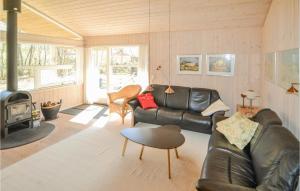 a living room with a leather couch and a fireplace at Holiday Home Kalvehavestien Glesborg Iii in Fjellerup Strand +9 photos