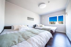 two beds in a room with two windows at THE SUN LOUNGE in Kushiro
