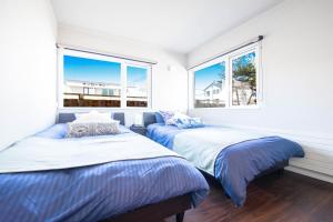 two beds in a bedroom with two windows at THE SUN LOUNGE in Kushiro