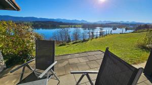 - deux chaises sur une terrasse avec vue sur le lac dans l'établissement Lechbruck am See Feriendorf Hochbergle Haus 43, à Lechbruck am See