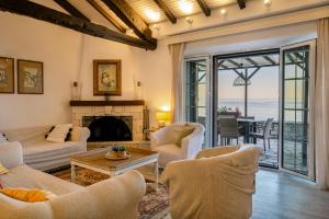 a living room with white furniture and a view of the ocean at Nissaki Olive Press Villas in Nisakion